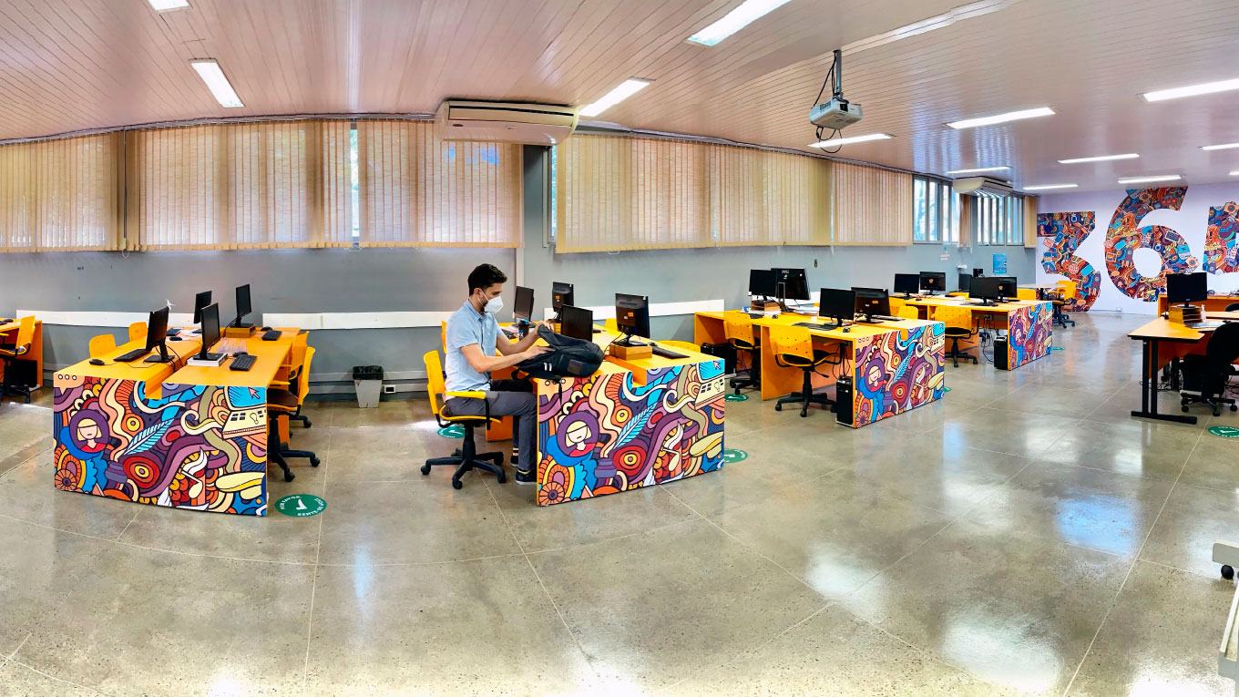 Vários estudantes utilizam computadores de um laboratório.