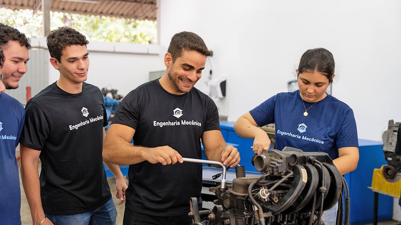 Estudantes manipulam engrenagem mecânica