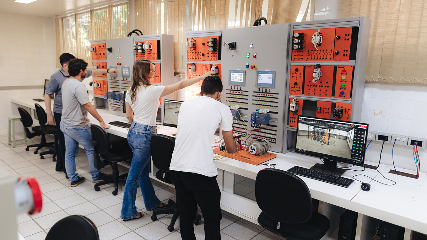 Jovens manipulam equipamento em laboratório de automação