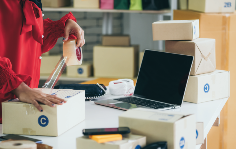 Vendedor online trabalha em home office e embala caixa de entrega de envio para o cliente.