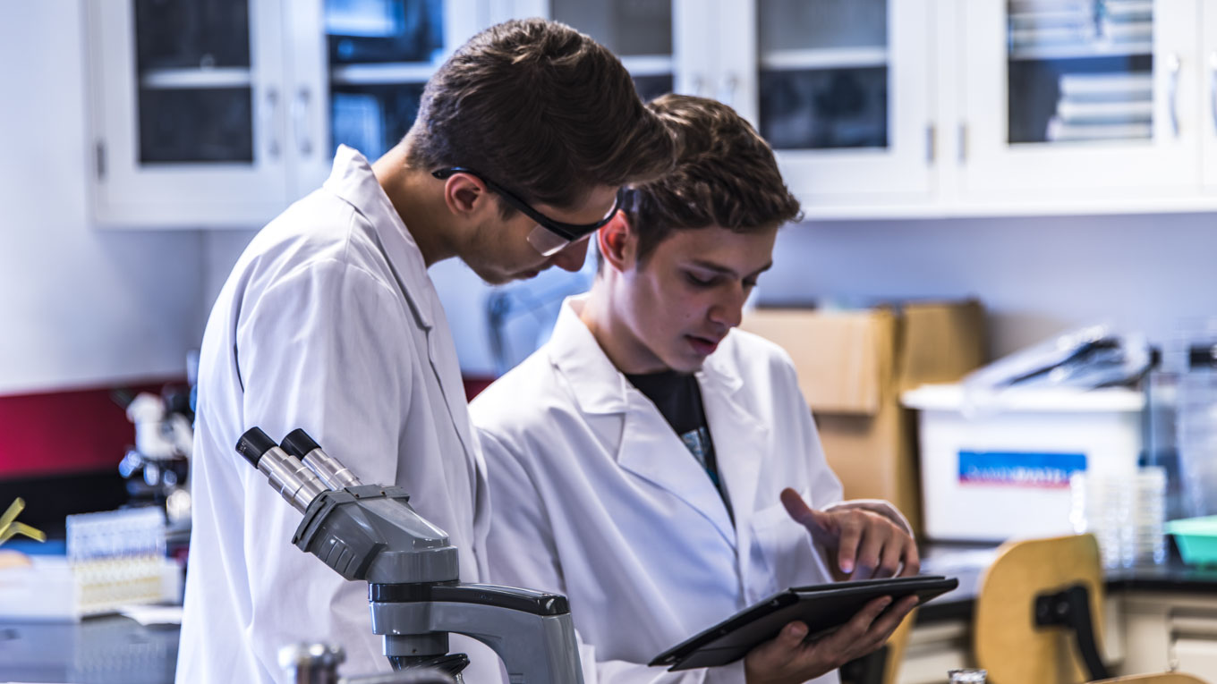 Dois estudantes analisam uma pesquisa num laboratório.