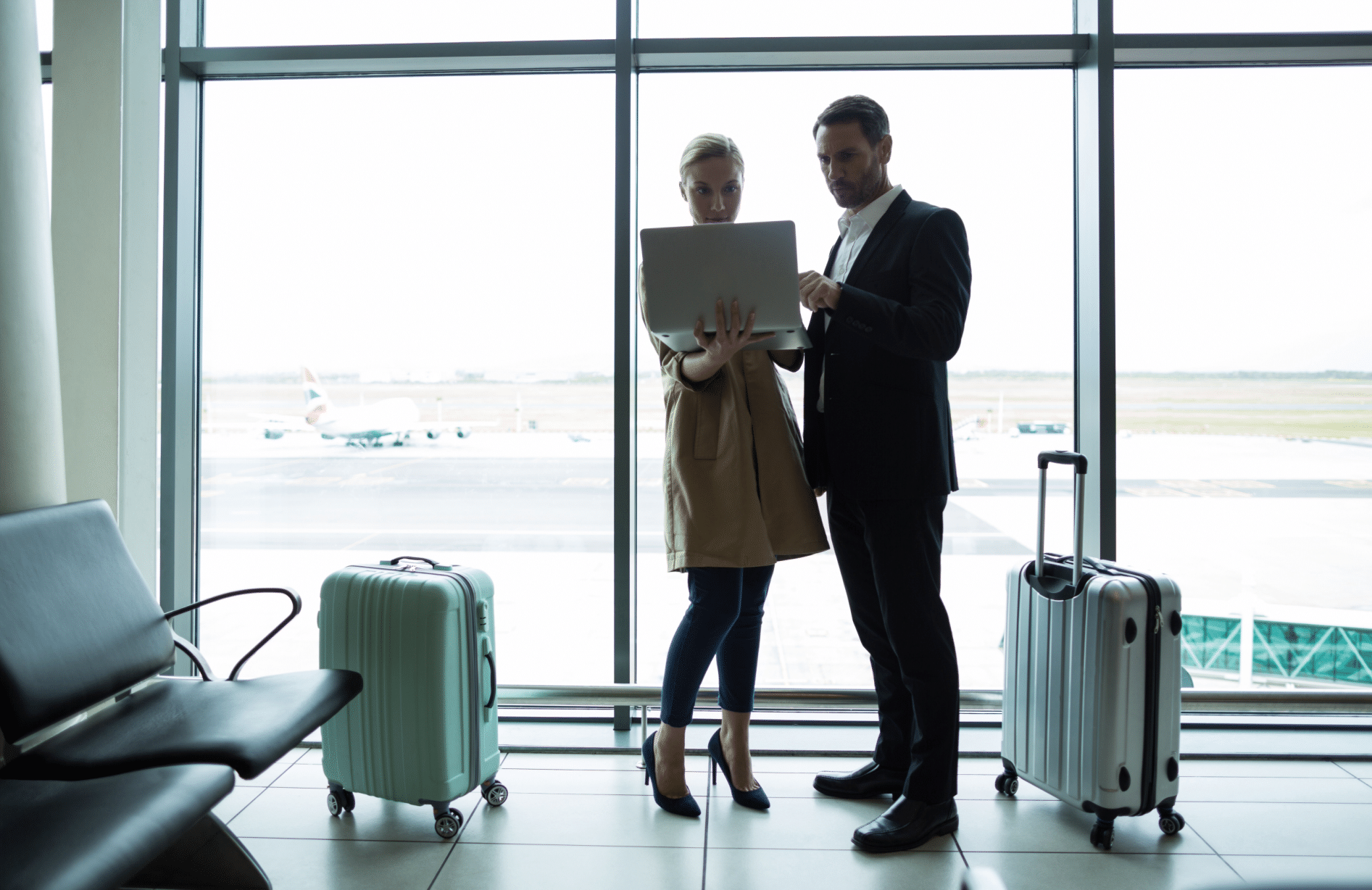 Duas parceiras de negócios, indo viajar carregando malas enquanto caminham pela passagem do aeroporto