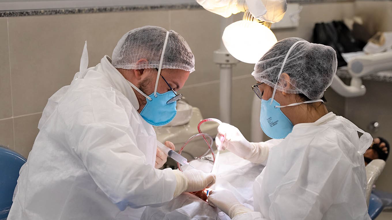 Dentistas examinando boca de paciente.